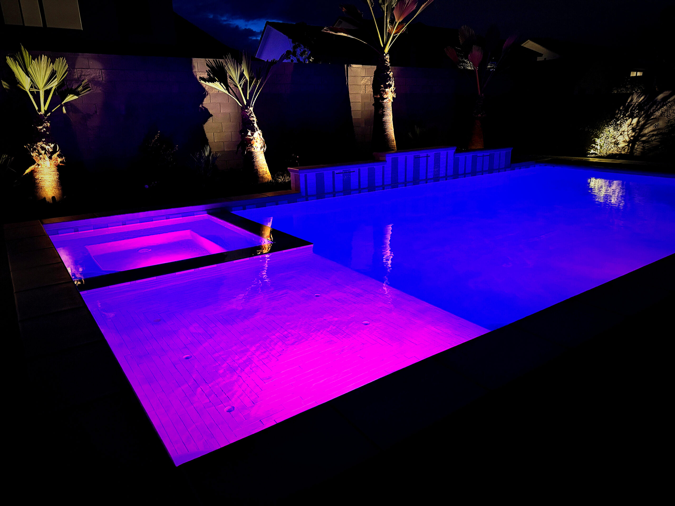 Custom pool illuminated at night with programmable LED lighting showcasing warm ambient glow by Paragon Pools