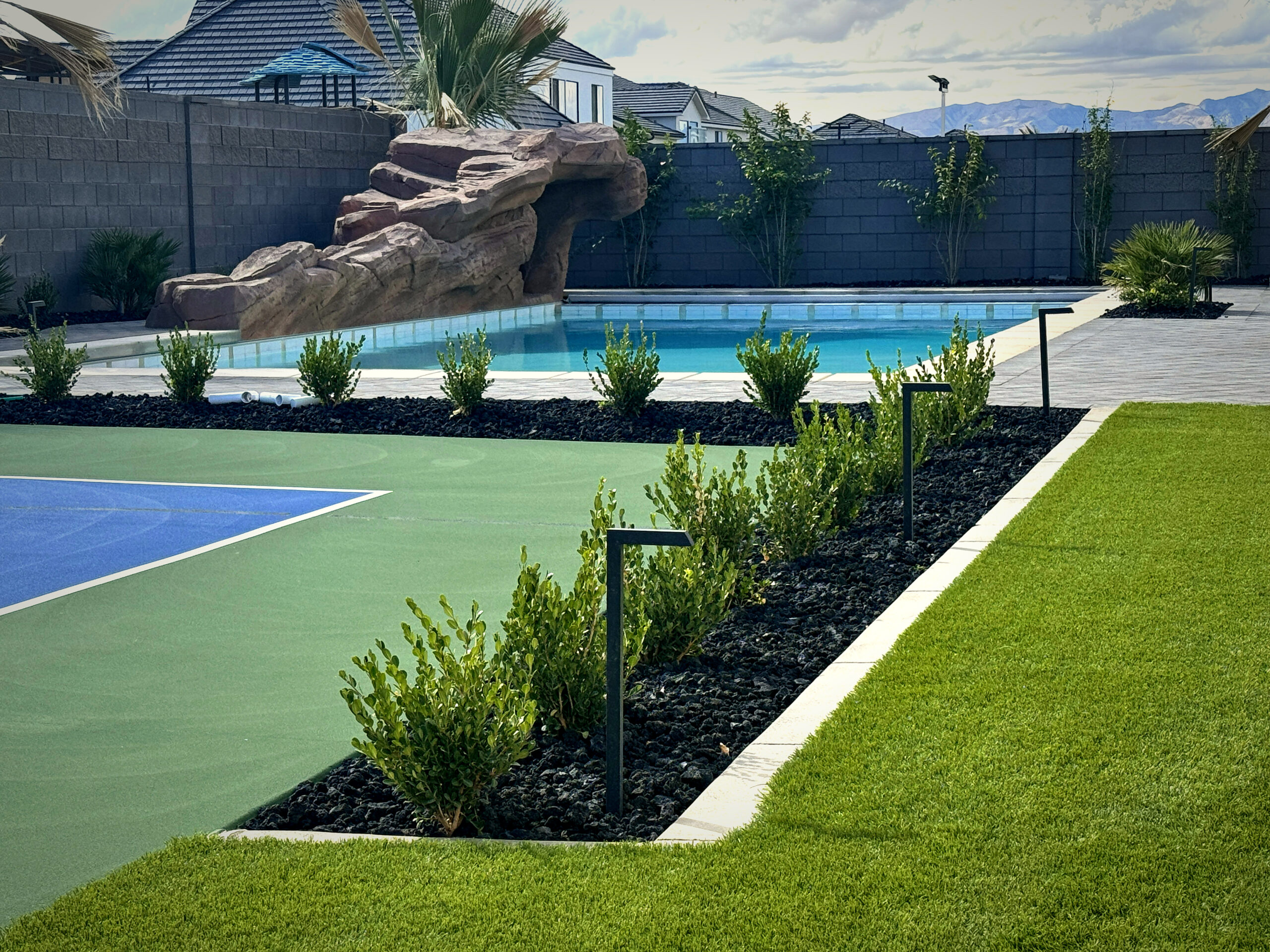 Luxury pool with rock grotto and water feature at golden hour by Paragon Pools