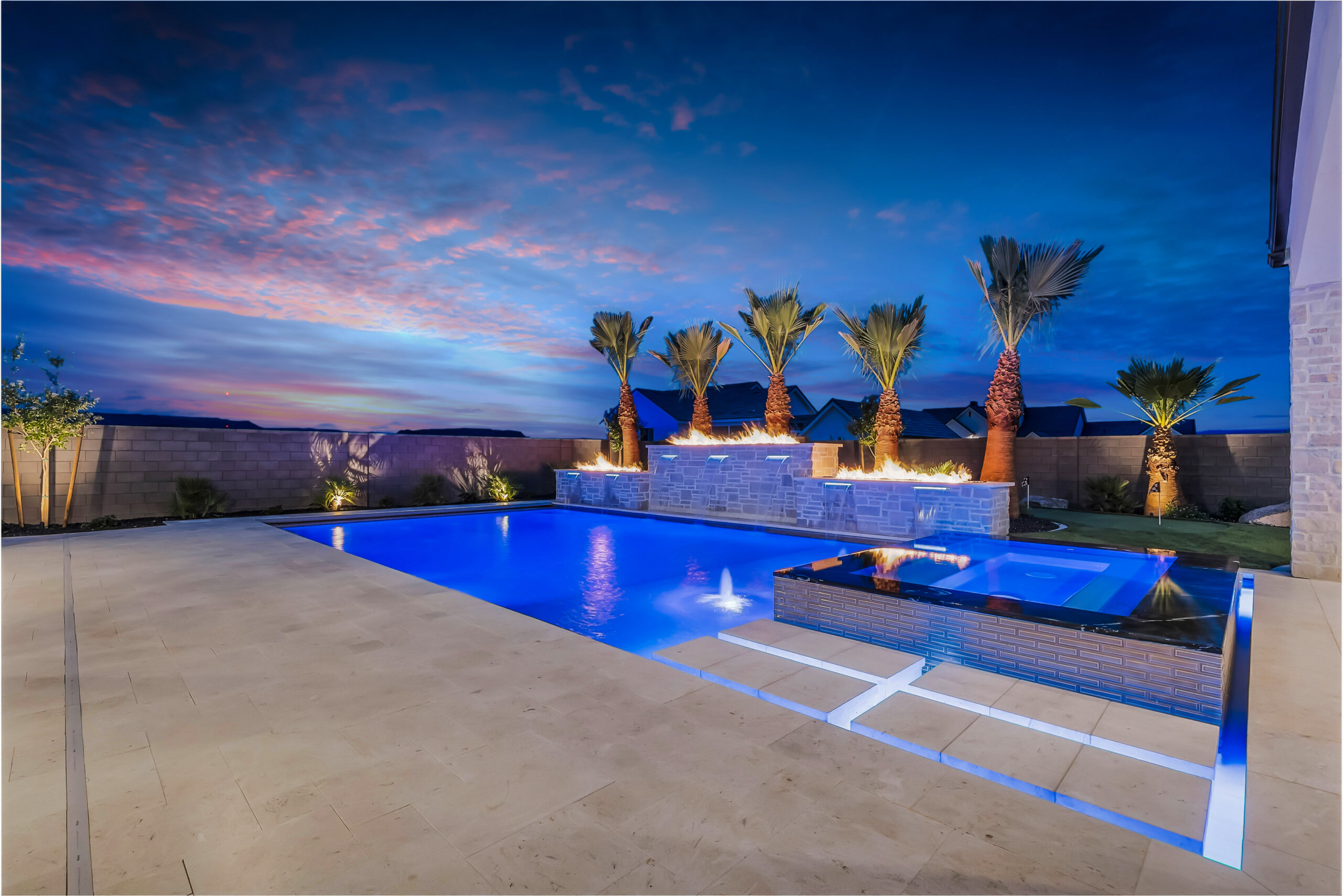 Twilight view of a custom pool with fire bowls, raised wall and covered ramada built by Paragon Pools in St. George, Utah