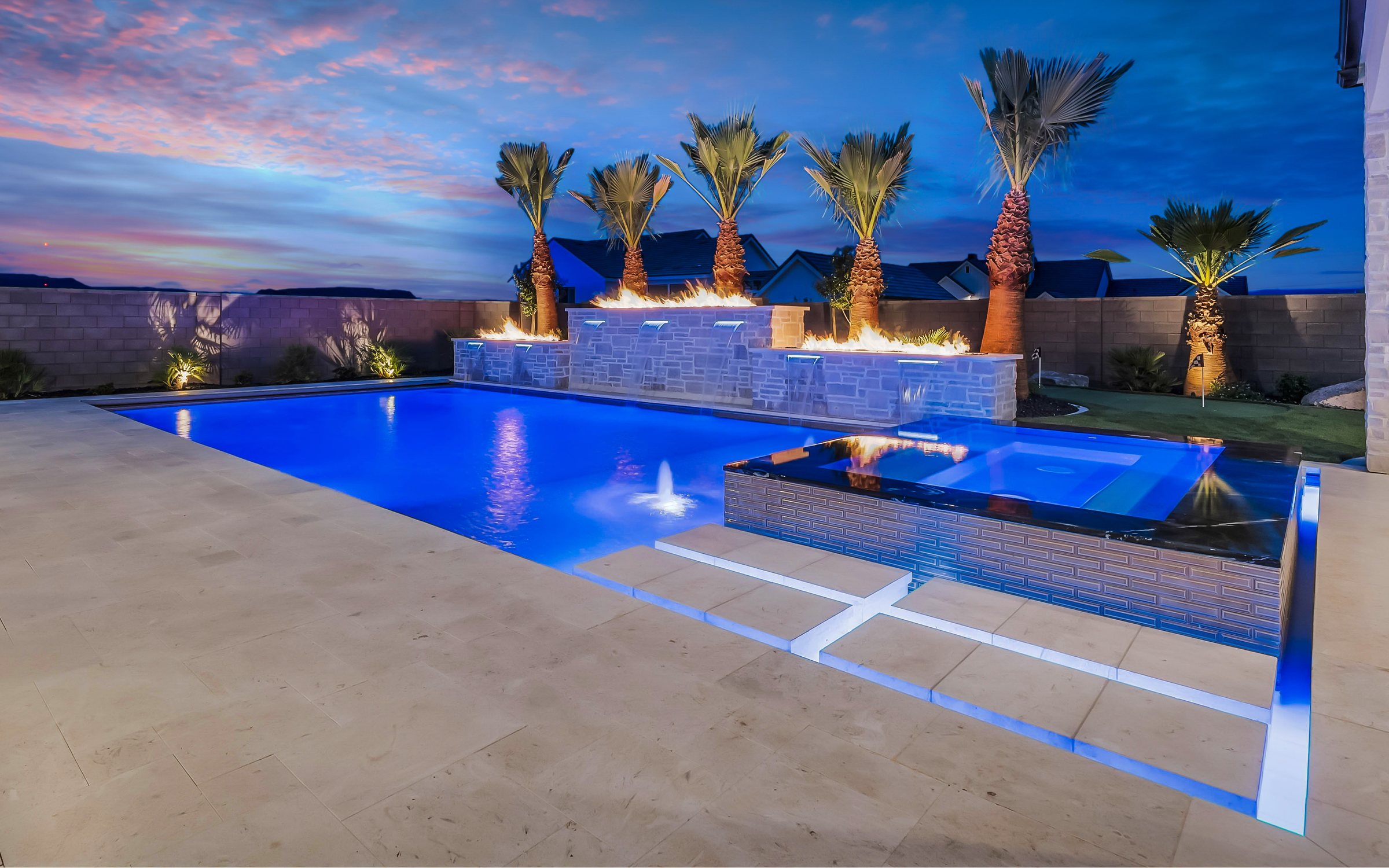 Custom pool and raised spa at twilight with fire bowls and sheer descents, built by Paragon Pools in St. George, Utah